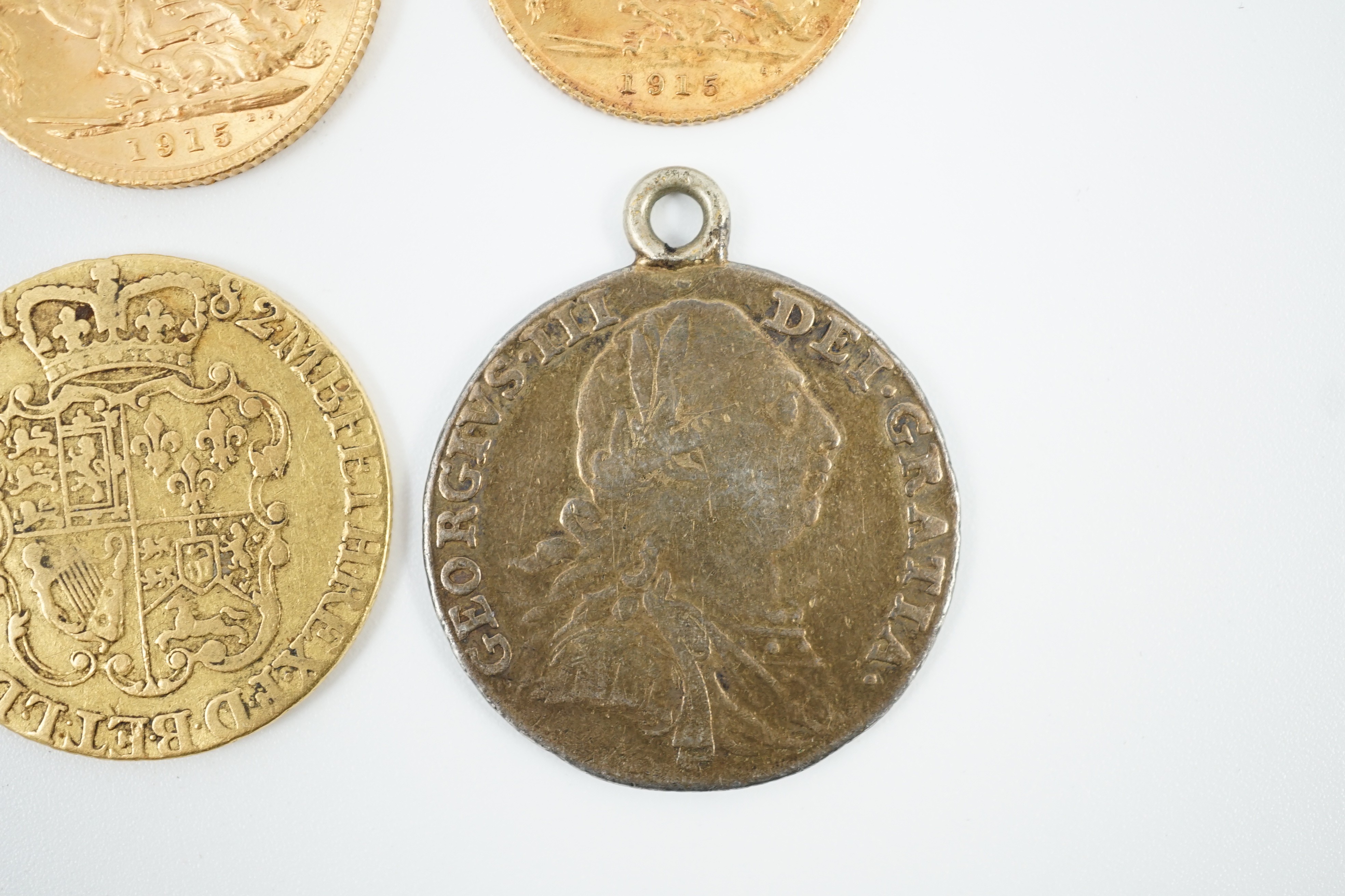 A George V 1915 gold sovereign and a 1915 gold half sovereign, a George III 1782 gold guinea(worn) and a George III 1787 shilling, with pendant mount.